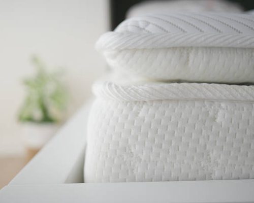 Soft white mattresses are neatly arranged on a contemporary bed frame.